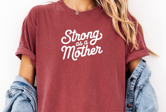 Maroon t-shirt with 'Strong as a Mother' text worn by a person, with a denim jacket over shoulders.