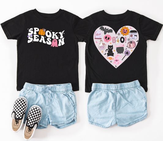 Our girly Spooke Season tee is covered in cute Halloween icons like playful cats, fluttering bats, cheerful pumpkins, and magical cauldrons.