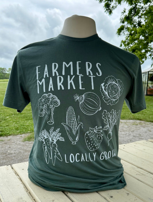 Green t-shirt with 'Farmers Market Locally Grown' text and vegetable illustrations on a wooden surface.